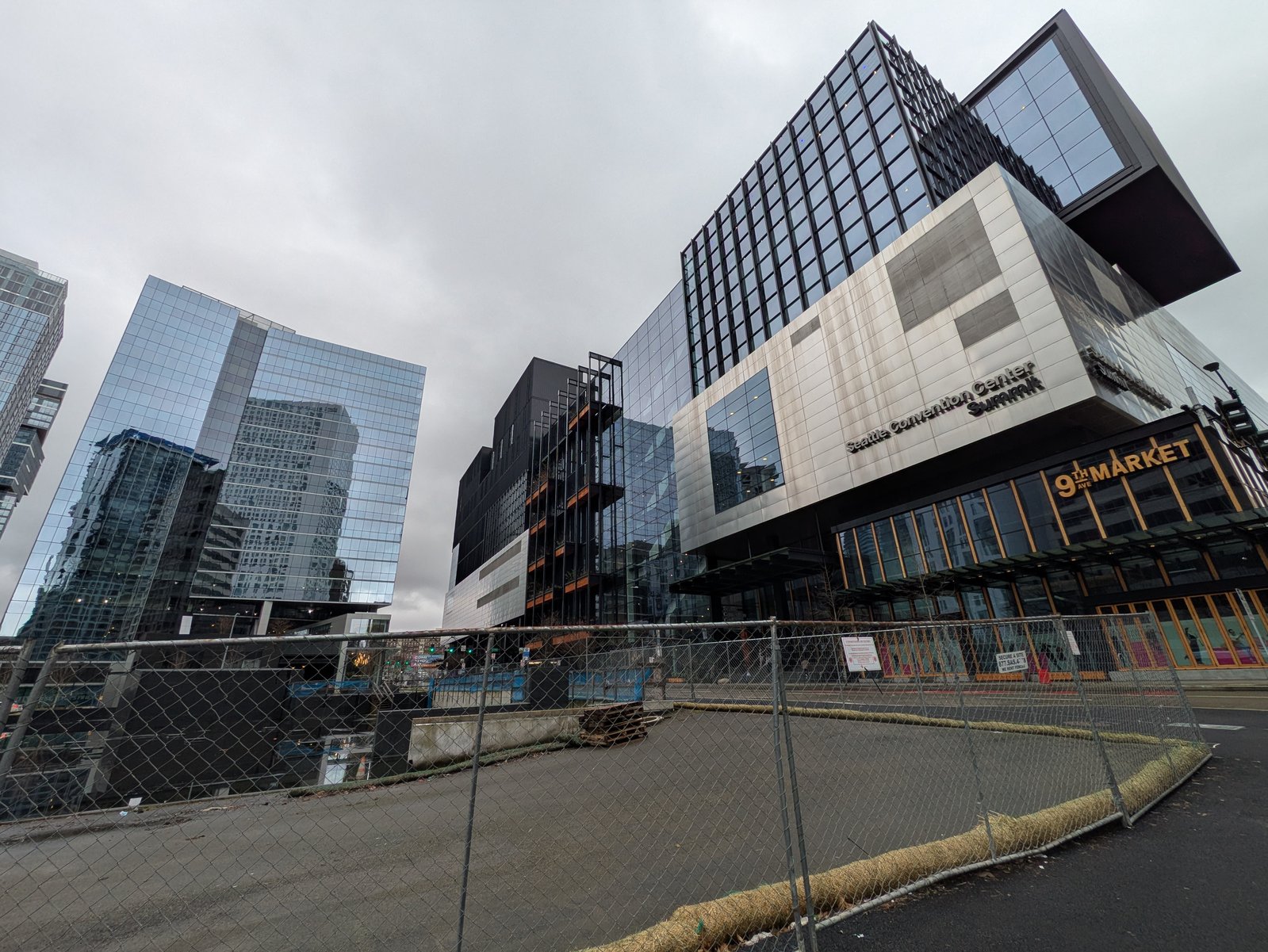 The Seattle Convention Center Summit, at 9th & Pike, seen past a construction fence — the public asset these seats govern.