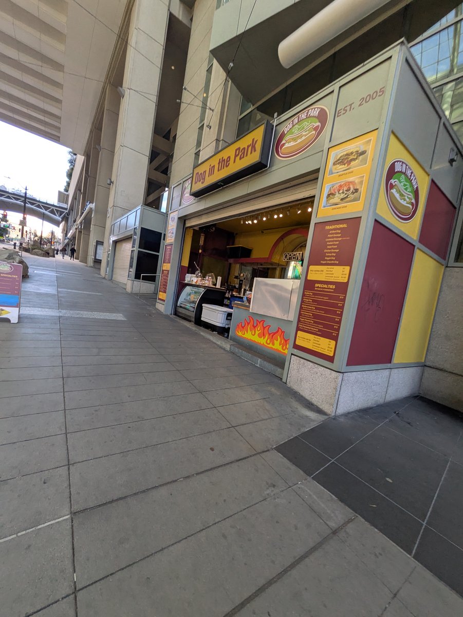 Dog in the Park — the hot-dog stand built into the convention center's Pike Street frontage, across from the former Cheesecake Factory. (February 2026.)